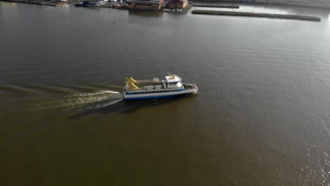 aerial view over gothenburg river in sweden, overlooking a ferry boat passing by from left to right on a beautiful sunny day, wide shot, transport concept