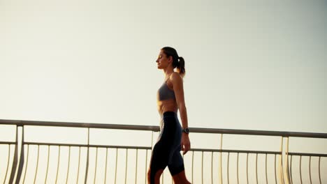 Ein-Fittes-Mädchen-In-Einer-Sommersportuniform-Geht-Morgens-An-Einem-Gitterzaun-Entlang.-Morgenspaziergang,-Morgens-Sport-Treiben