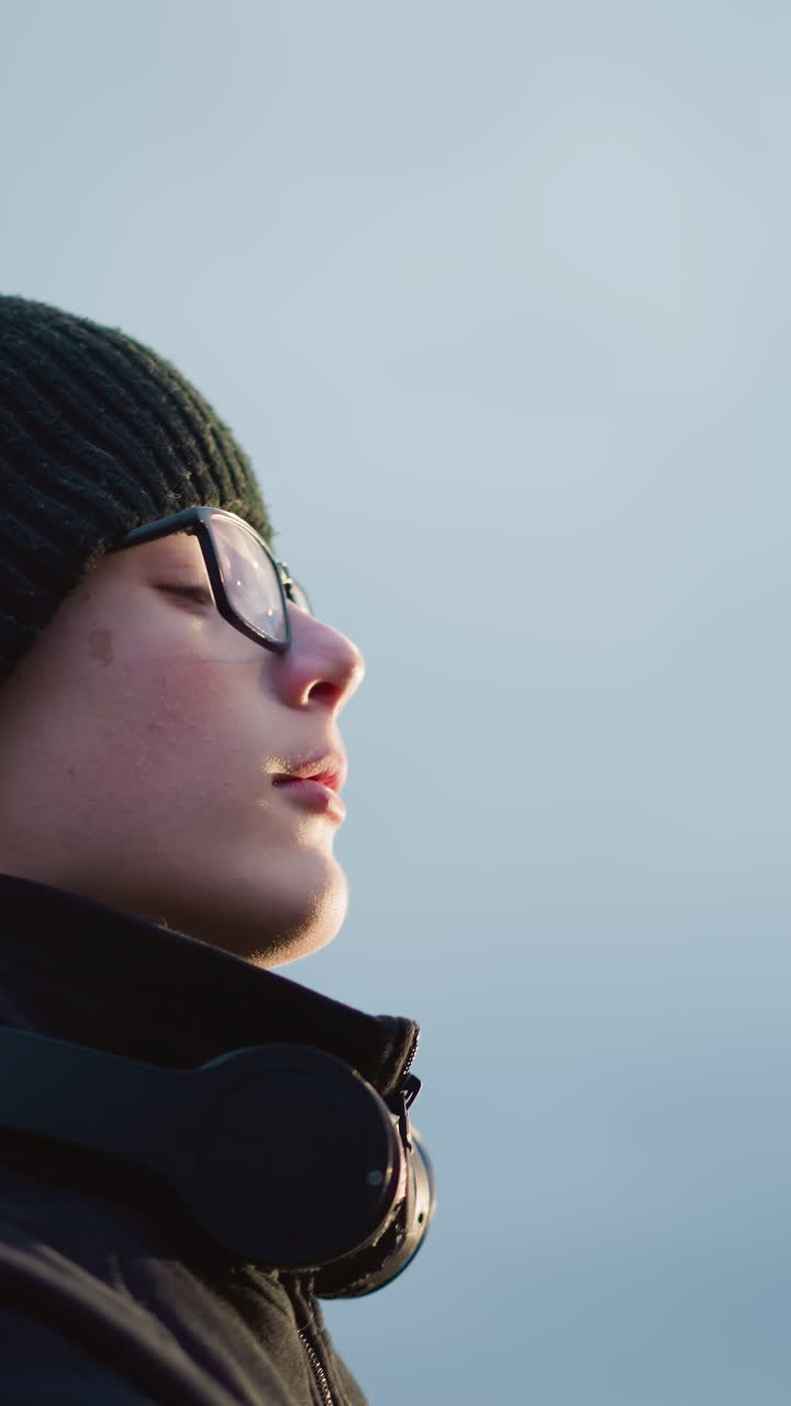 vista lateral de un niño en un traje negro y gafas levantando una pelota con un auricular alrededor de su cuello, con la boca ligeramente abierta
