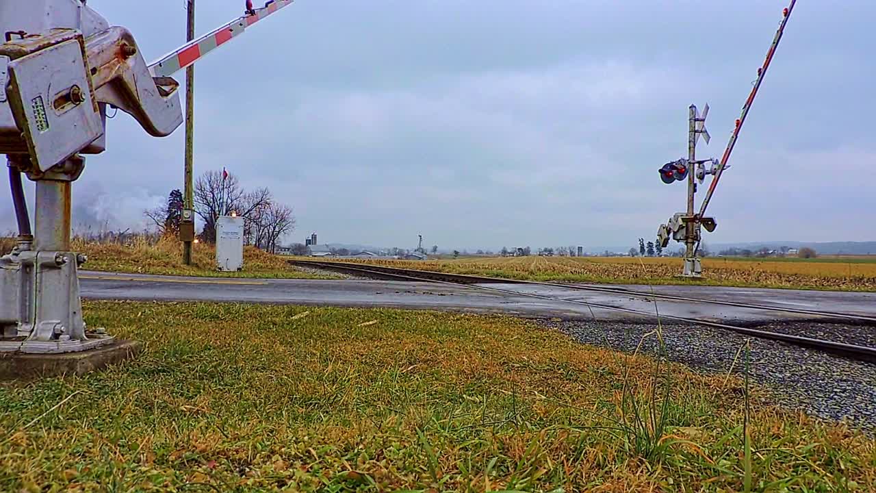 겨울날 건널목이 낮아지면서 불어오는 증기에 접근하는 골동품 증기 여객 열차의 낮은 각도