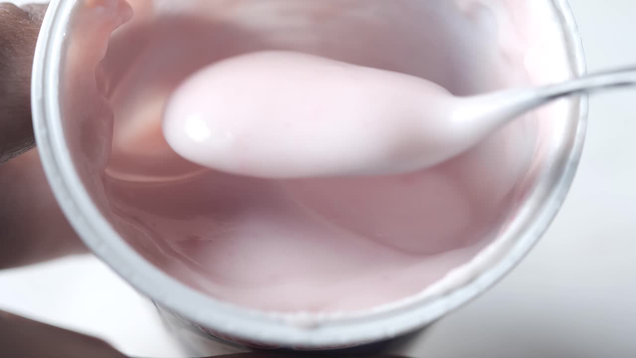 yogur rosa en un recipiente con cuchara