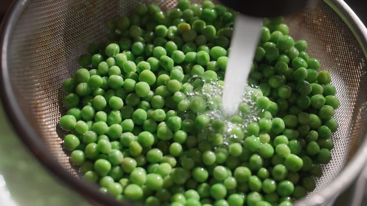 Groene erwten worden gespoeld ter voorbereiding op een Beef Wellington (slow motion 4K).