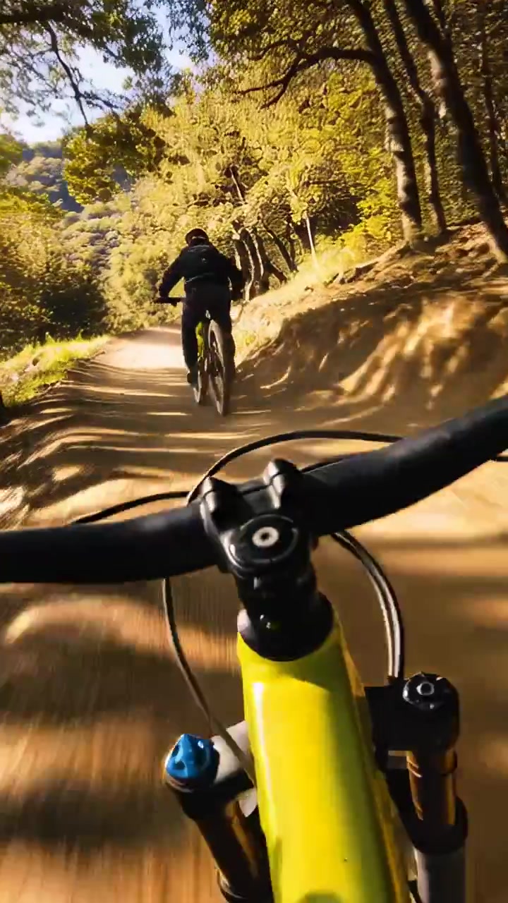 Video verticale: Seguendo un ciclista con casco che pedala su rilievi su un sentiero in collina, con telaio giallo.