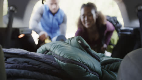 Happy-african-american-couple-taking-camping-equipment-from-car-trunk,-slow-motion