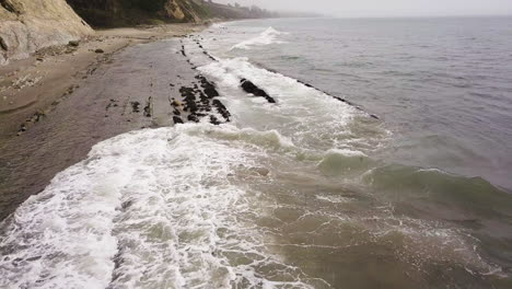 wild shore waves hittting the rocks of california coast aerial