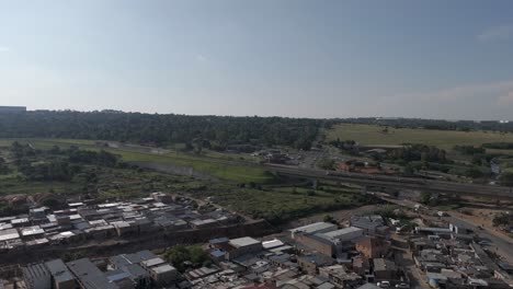 push-in drone shot glides over the township of alexandra in johannesburg as a high-speed train swiftly passes by, offering a glimpse of the energetic cityscape and rapid transportation in motion