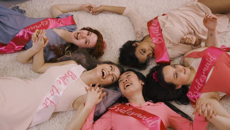 top view of bachelor girl and her friends holding hand lying on the carpet 1