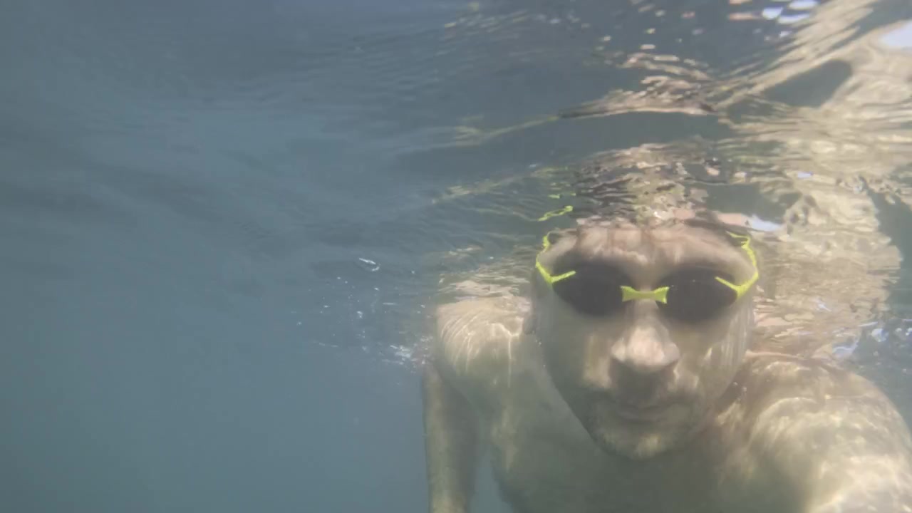 Man swimming underwater in clear blue water, enjoying a refreshing aquatic activity and healthy lifestyle
