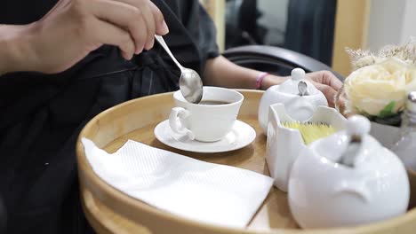 Chica-Preparando-Su-Taza-De-Café-En-Una-Elegante-Bandeja-De-Madera,-Detalles-De-Tomas