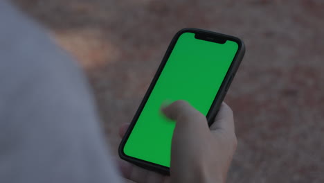 Mann-Wischt-Auf-Einem-Smartphone-Mit-Grünem-Bildschirm,-Nahaufnahme