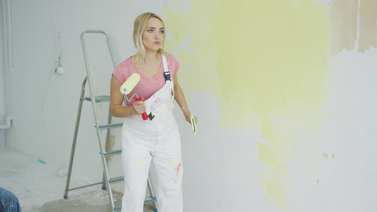 mujer rubia con rodillo de pintura bailando