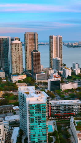 beautiful high-rise and low-rise buildings in miami beach, florida, usa. top view. blue waterscape of the atlantic ocean at backdrop. vertical video