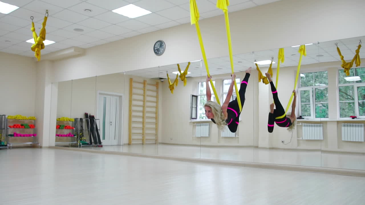 건강한 생활 방식을 위한 스포츠의 개념. 소녀는 안티그래비티의 에어로로지와  ⁇ 색 방에서 캔버스에 흔들리고 있습니다. 캔버스의 축을 중심으로 회전