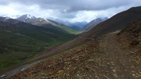 drone shot of a tuk tuk on babusar pass in pakistan, with a few vehicles on the road below in the kaghan valley