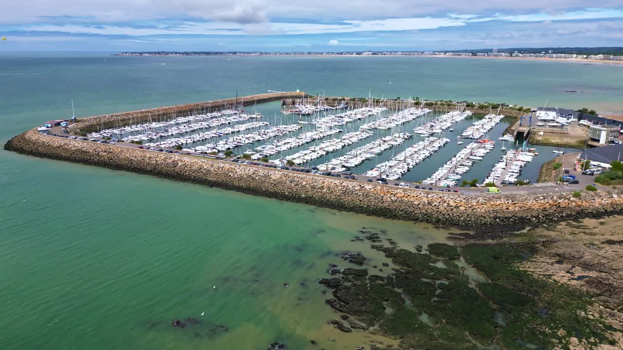Pornichet marina at low tide, sailboats, breakwater, and tidal flats, France. Aerial ascending