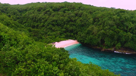 exotic beach with turquoise sea hidden behind cliff with dense foliage