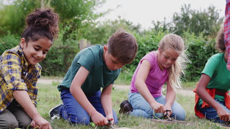 team leader showing group of children on outdoor camping trip how to make fire