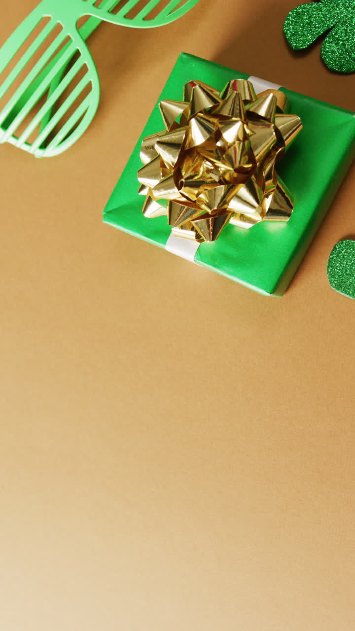 Vertical video of of st patrick's green glasses and present with copy space on orange background