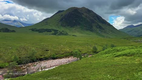 green mountainous terrain on the remote trails through glencoe in western scotland. panning shot
