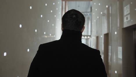 man walking down a modern office corridor