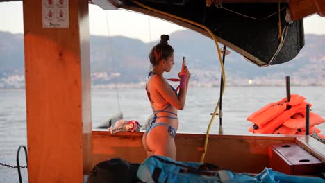 mujer en bikini tomando fotos desde un barco