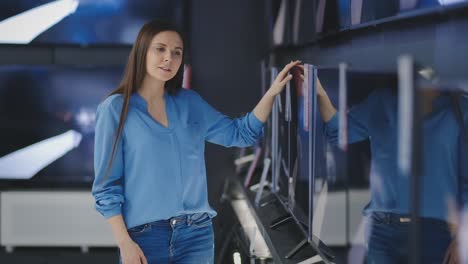 smart modern female customer choosing large tv-sets at electronics store. new screen generations