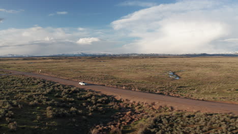 White-car-driving-on-wide-open-road-through-empty-Idaho-countryside