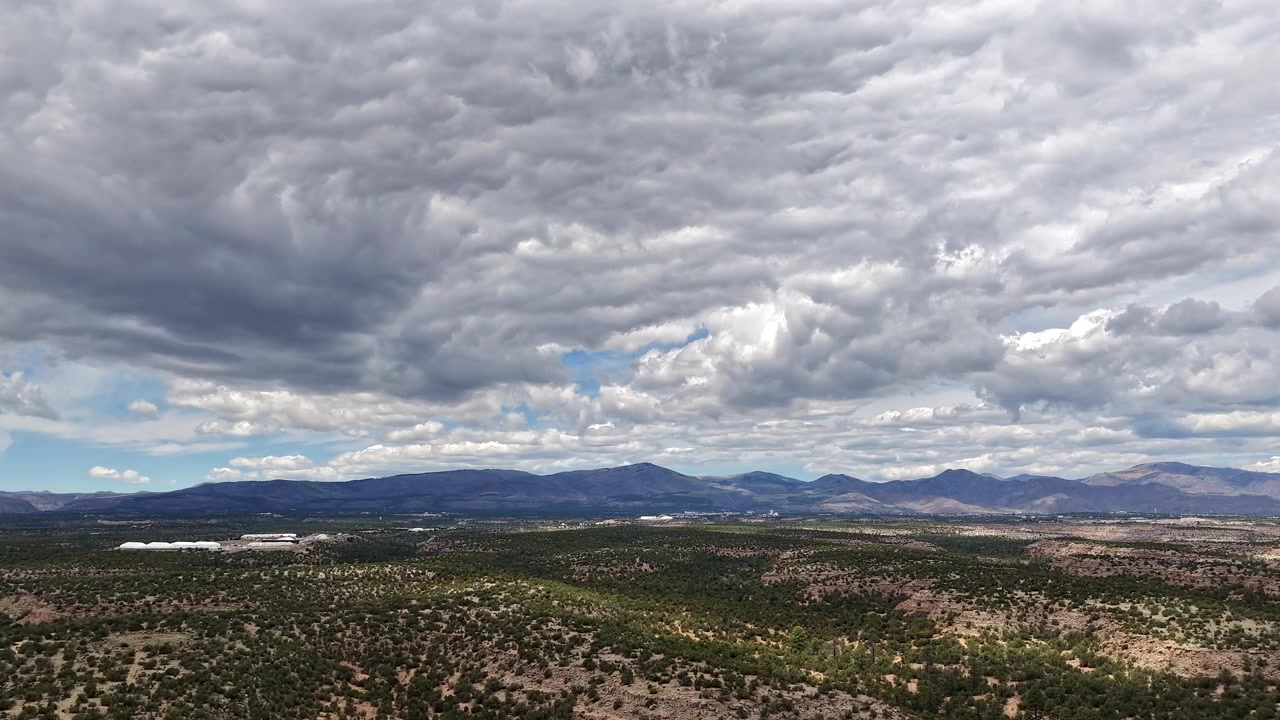 Un timelapse 4K con drone cattura nuvole dall'aspetto fiabesco che si muovono su aspre montagne e mesas del sud-ovest. Il paesaggio celeste cinematografico rivela una luce atmosferica cangiante e panorami naturali desertici ad alta quota.