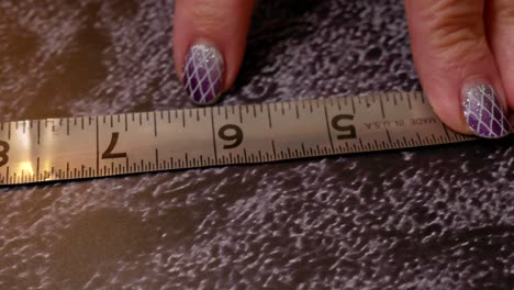 Close-up-of-a-woman's-hands-opening-a-tape-measure-and-pointing-at-numbers