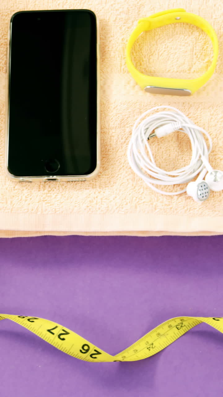 teléfono móvil con auriculares, zapatos, botella de agua, banda de fitness, estera de ejercicio y cinta métrica