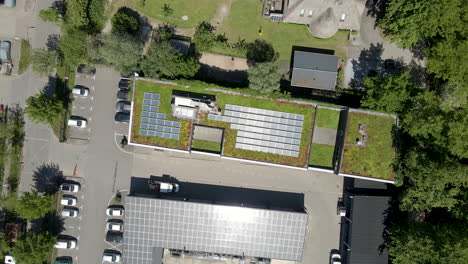 top down aerial of solar panels on a green rooftop - drone lifting up