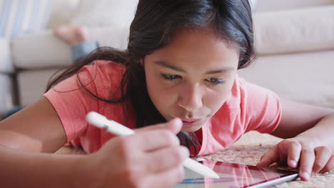 Teenager-Mädchen-Liegt-Im-Wohnzimmer-Auf-Dem-Boden-Und-Benutzt-Einen-Tablet-Computer-Und-Einen-Stift,-Nahaufnahme