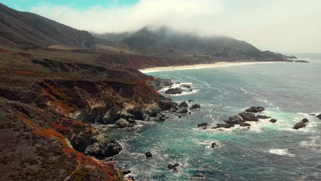 Drone-aerial-flight-view-of-sapphire-sea-on-the-Big-Sur-Coastline-west-California-next-to-route-1-with-powerful-crashing-waves