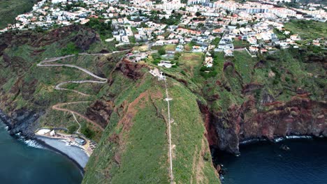 Aerial-view-tilting-up-over-Ponta-du-Garajau-green-island-coastline,-Madeira,-Portugal