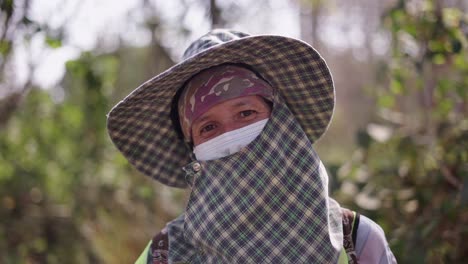 person wearing a hat, face mask, and protective clothing outdoors