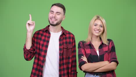 young happy couple showing something together