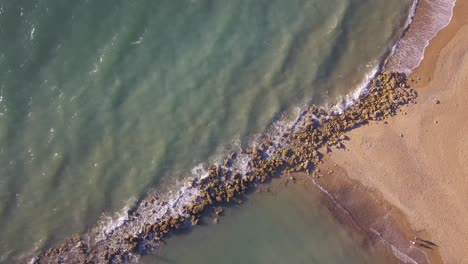 Waves-Washing-Rocks-And-Sandy-Beach,-Espigon-de-Sancti-Petri-In-Chiclana-de-la-Frontera,-Cadiz,-Spain--aerial-top-down