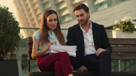 Colleagues-looking-at-documents-on-street.-Partners-discussing-financial-papers