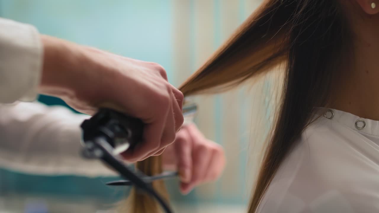 Handheld view of hairdresser using straightener and comb