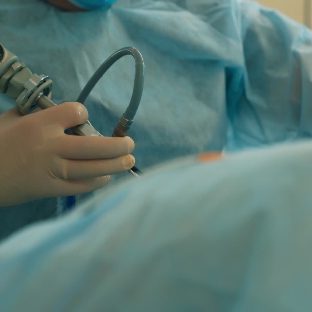 Unrecognized surgeon wearing latex gloves holding electric tool. Doctor using device instrument at work. Close up