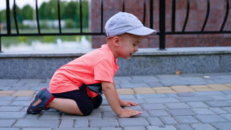 funny toddler boy crawling by the paved road in the park. cheerful kid having fun outdoors in summer.
