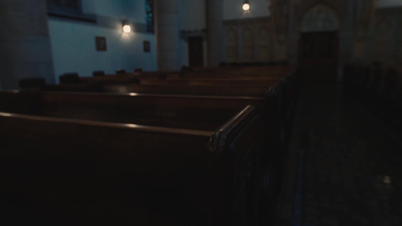 Interno di chiesa scarsamente illuminato con banchi di legno vuoti