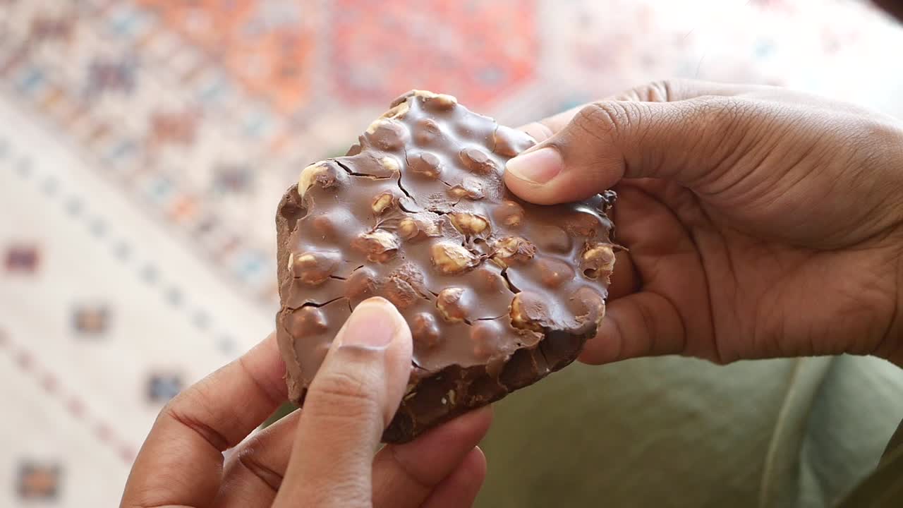 cerca de las manos sosteniendo una barra de chocolate con avellanas