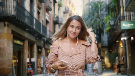 Mujer-Feliz-Caminando-En-Auriculares-En-Cámara-Lenta.-Linda-Chica-Coqueteando-Al-Aire-Libre.