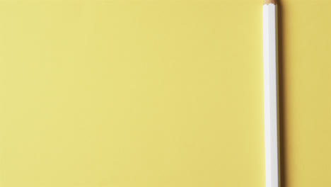 overhead view of white crayon with copy space on yellow background, in slow motion