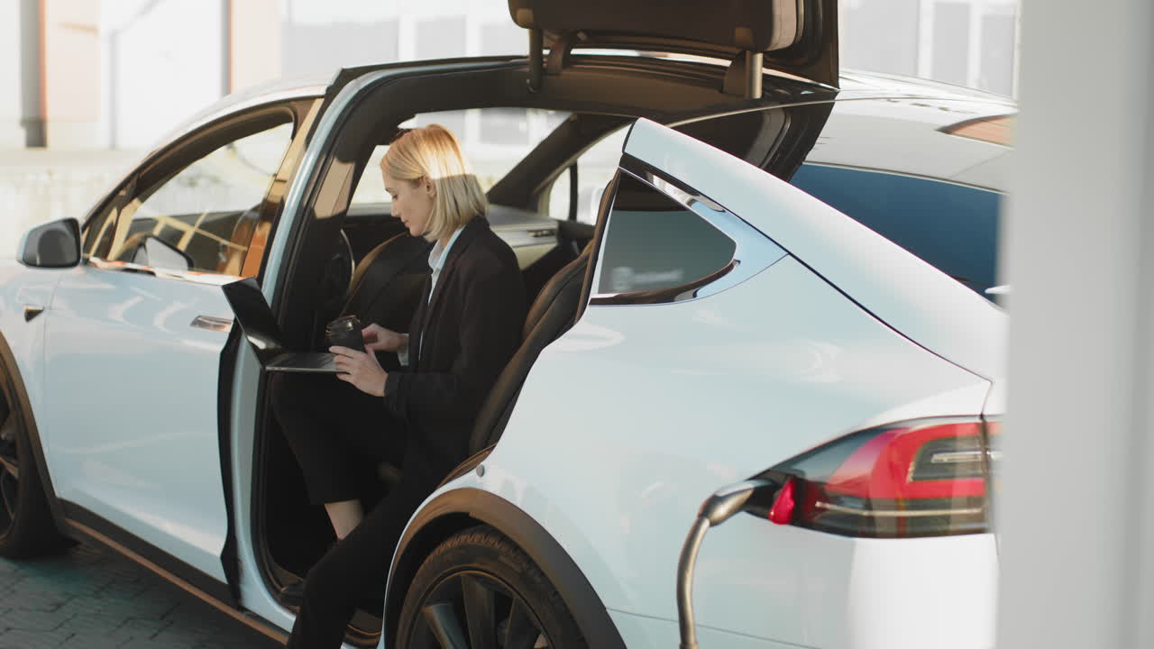 mujer trabajando en un coche eléctrico en una estación de carga