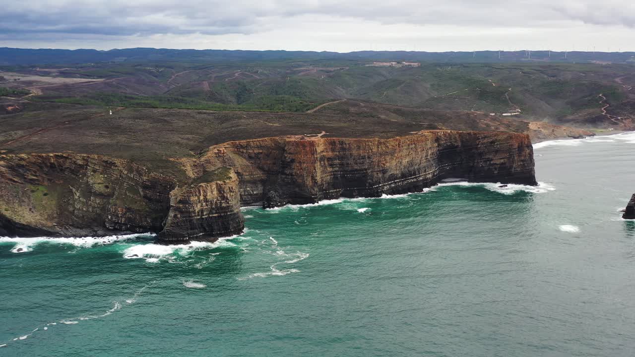 Praia da Arrifana cliffs showing strata in west Portugal Atlantic coastline, Aerial circle shot