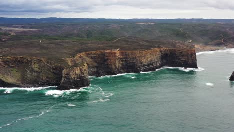 praia da arrifana cliffs showing strata in west portugal atlantic coastline, aerial circle shot