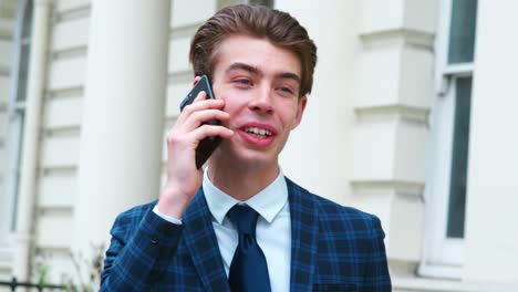 hombre elegante en traje se encuentra afuera del edificio usando teléfono móvil