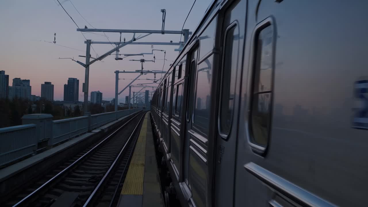 Dynamic video of a train moving on elevated tracks at dusk, captured from a side angle